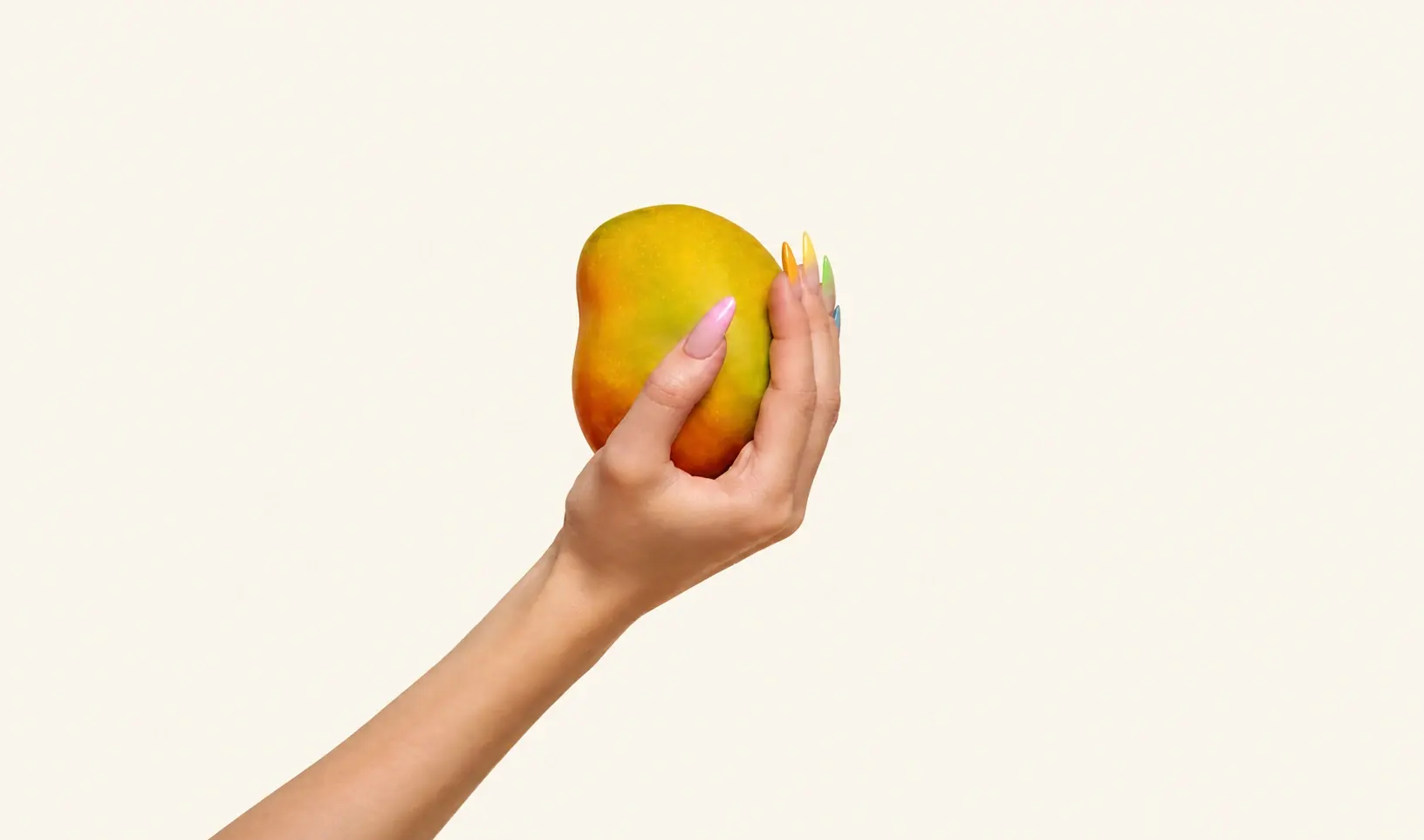 A hand with colourful nails holding a mango